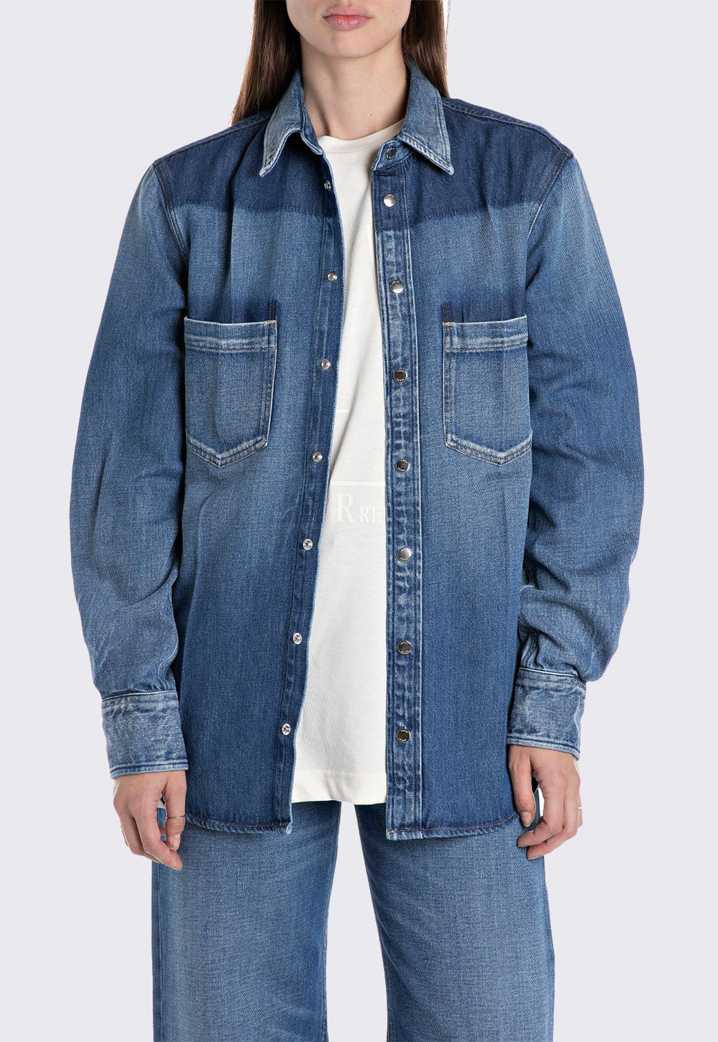 חולצת נשים ארוכה מבד ג’ינס כחול עם כיסים קדמיים וכפתורים.