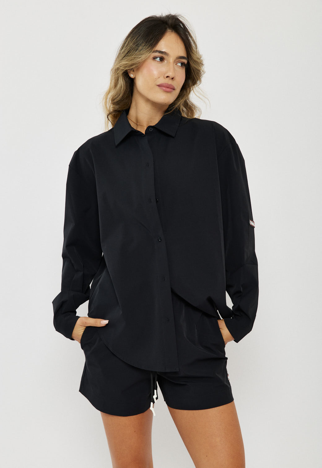 דוגמנית לובשת חולצה מכופתרת לנשים בצבע שחור עם שרוולים ארוכים