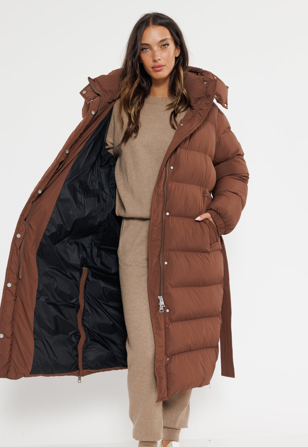 מעיל פוך ארוך לנשים בצבע שוקולד עם קפוצ'ון, רוכסן מלא וחגורת קשירה במותן.